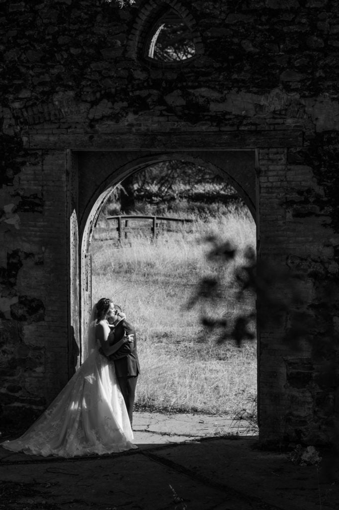 Black and white photo of bride and groom standing in an abandon doorway