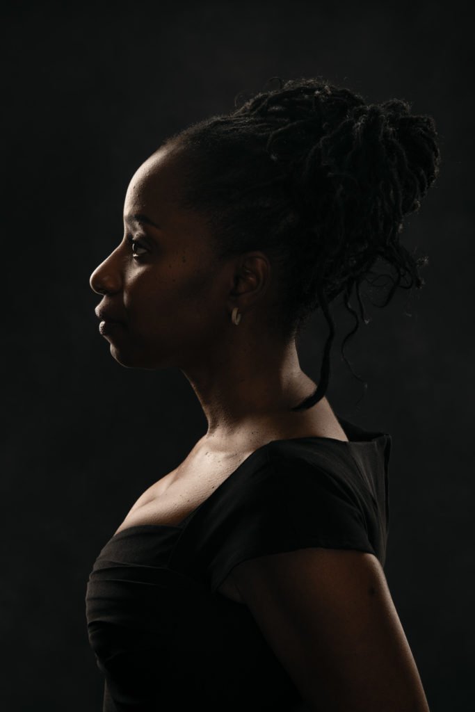 Profile portrait of a black woman on black background