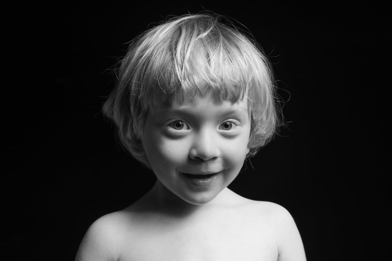 black and white portrait of a little boy on a black background